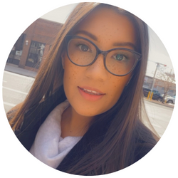 Photo of Andrea Salazar, a UCR student with dark hair, wearing glasses and smiling at the camera